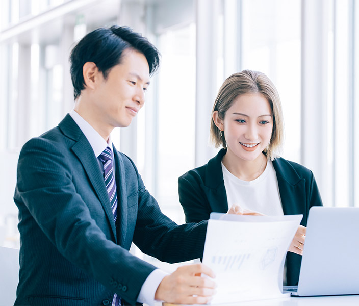 ノートPCを見ながら指導しているビジネスマン